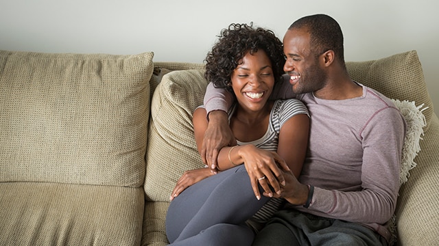 Un couple enlacé et souriant sur le canapé