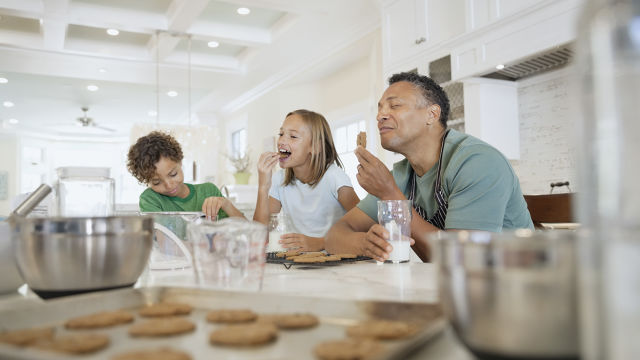 Un père et ses enfants mangeant des biscuits, heureux