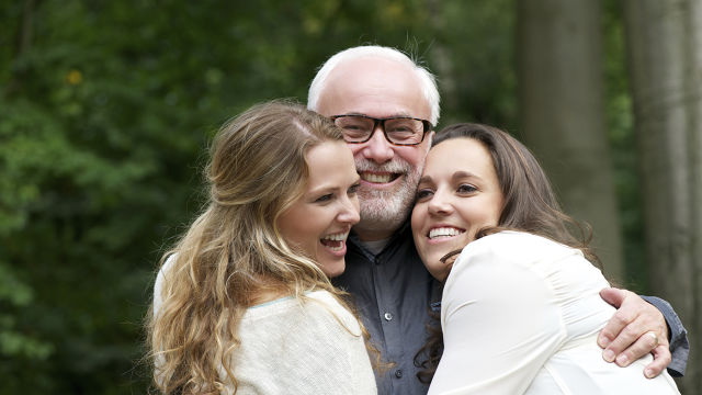 Un père et ses deux filles s'embrassant et souriant