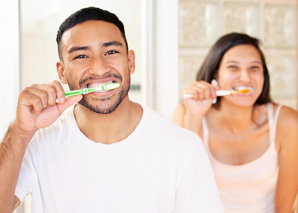 een man en een vrouw poetsen hun tanden samen met een glimlach